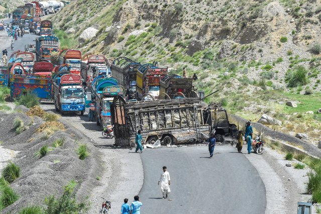 People look at a charred vehicle near a collapsed railway bridge a day after a blast by separatist militants at Kolpur in Bolan district, Balochistan province on August 27, 2024. Pakistani forces hunted separatist militants on August 27, who killed dozens when they pulled passengers off buses, blew up a bridge and stormed a hotel a day earlier. Militants in Balochistan took control of a highway and shot dead 23 people, mostly labourers from neighbouring Punjab province, attacked the hotel and the railway bridge which connects Balochistan to the rest of Pakistan. (Photo by Banaras Khan/AFP Photo)