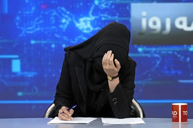TV anchor Khatereh Ahmadi bows her head while wearing a face covering as she reads the news on TOLO NEWS, in Kabul, Afghanistan, Sunday, May 22, 2022. Afghanistan's Taliban rulers have begun enforcing an order requiring all female TV news anchors in the country to cover their faces while on-air. The move Sunday is part of a hard-line shift drawing condemnation from rights activists. (Photo by Ebrahim Noroozi/AP Photo)