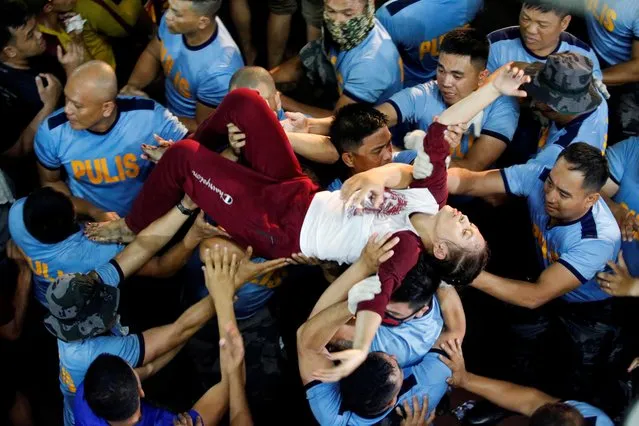 A Filipino devotee is carried by police officers outside the Quiapo church after she fainted during the Black Nazarene feast day in Manila, Philippines, January 9, 2020. (Photo by Willy Kurniawan/Reuters)