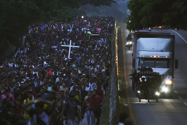 Migrants, many from Central American and Venezuela, walk along the Huehuetan highway in Chiapas state, Mexico, early Tuesday, June 7, 2022. The group left Tapachula on Monday, tired of waiting to normalize their status in a region with little work and still far from their ultimate goal of reaching the United States. (Photo by Marco Ugarte/AP Photo)