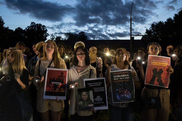 Ukrainians hold lights during a memorial event in front of the closed Russian Embassy on July 29, 2023 in Kyiv, Ukraine. The memorial marks the one year anniversary of the Olenivka prison attack, when dozens of Ukrainian soldiers died during an attack of Olenivka in the eastern Donetsk region during the Russian invasion of Ukraine. (Photo by Paula Bronstein /Getty Images)