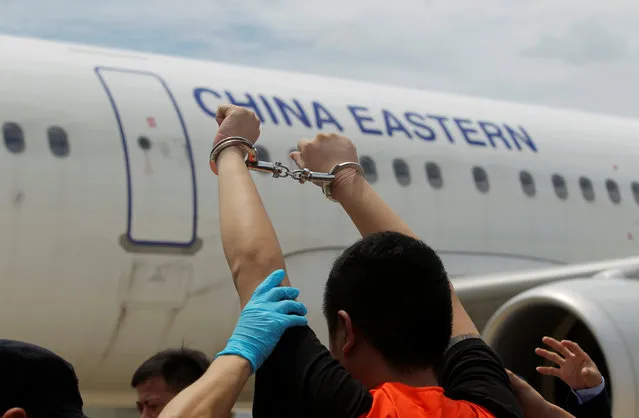 A suspect of telecom fraud lifts his hands up as he is deported to China at the International Airport of Phnom Penh, Cambodia June 24, 2016. (Photo by Samrang Pring/Reuters)