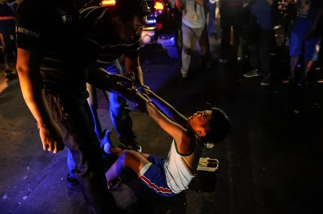 Social workers and police round up a minor at night during curfew, June 8, 2016, in Manila, Philippines. (Photo by Dondi Tawatao/Getty Images)