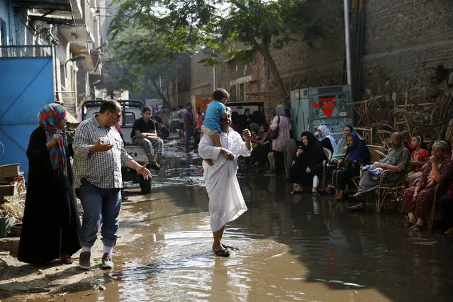 Egyptian families sit along a flooded street after they left their apartments that were damaged by a blast that also killed at least one person and crumbled  the facade of the Italian consulate, in Cairo, Egypt, Saturday, July 11, 2015. An Italian embassy official said the consulate was closed at the time of the explosion and no staff members were injured. (AP Photo/Hassan Ammar)