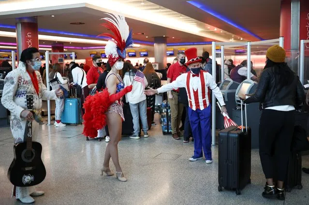 Performers engage with travellers as they queue to check into Virgin Atlantic and Delta Air Lines flights at Heathrow Airport Terminal 3, following the lifting of restrictions on the entry of non-U.S. citizens to the United States imposed to curb the spread of the coronavirus disease (COVID-19), in London, Britain, November 8, 2021. (Photo by Henry Nicholls/Reuters)