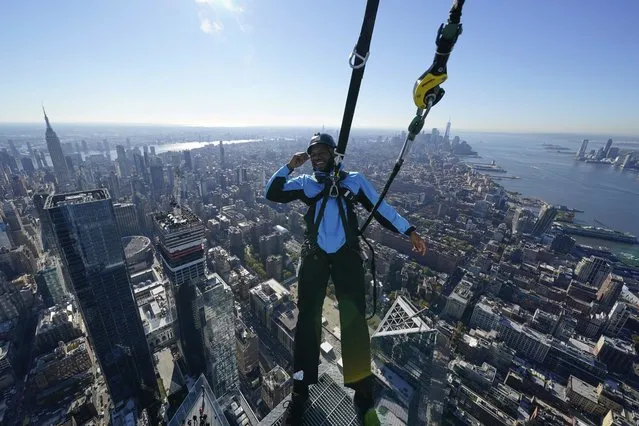 Climb guide Jason Johnson leans off the edge at the top of City Climb, a new attraction at 30 Hudson Yards in New York, Wednesday, November 3, 2021. The attraction opening Tuesday, Nov. 9 gives thrill-seekers a unique perspective on New York City from almost 1,300 feet up. At the top, a safety harness allows the climber to lean out over New York City and enjoy a panoramic view in the fresh air, unimpeded by glass. (Photo by Seth Wenig/AP Photo)
