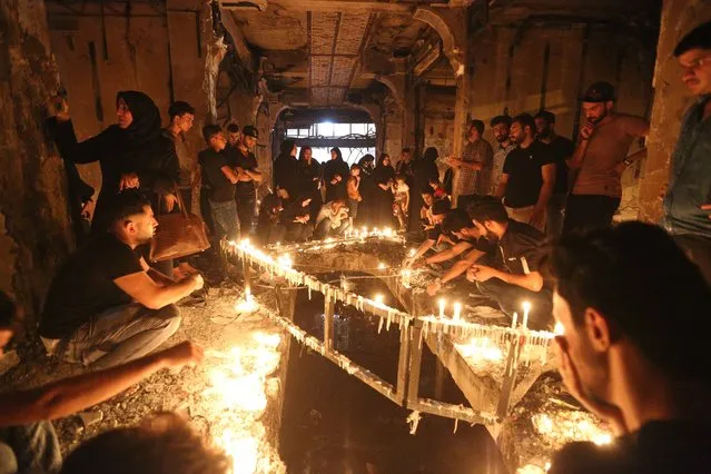 People light candles inside a mall at the scene of a massive truck bomb attack in Karada neighborhood, Baghdad, Iraq, Tuesday, July 5, 2016. Iraqis mourn for their dead and prepare for the Muslim holiday of Eid al-Fitr under the pall of one the worst bombings in 13 years of war. An Islamic State suicide bomber struck Baghdad's bustling commercial area of Karada on Sunday night, after people came out after breaking their daily fast. (Photo by Hadi Mizban/AP Photo)
