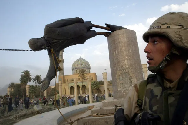 A U.S. soldier watches as a statue of Iraq's President Saddam Hussein falls in central Baghdad, Iraq April 9, 2003. (Photo by Goran Tomasevic/Reuters)