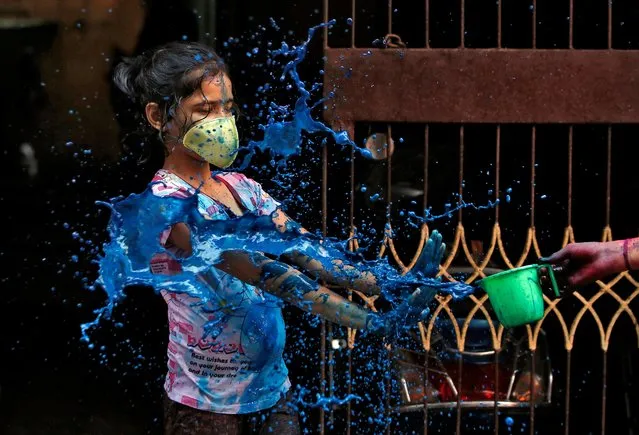 A girl wearing a protective mask reacts as she is splashed with coloured water during Holi celebrations amid coronavirus precautions, in Chennai, India, March 10, 2020. (Photo by P. Ravikumar/Reuters)