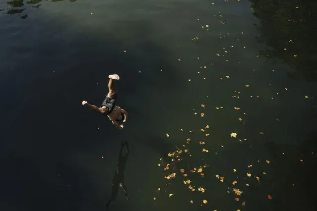 Kids jump from a bridge to swim in the Canal St Martin, during a heatwave in Paris, Monday, July 18, 2022. (Photo by Lewis Joly/AP Photo)