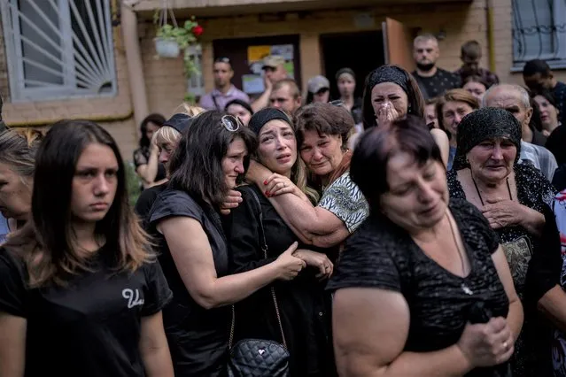 Anastasia Ohrimenko, 26, is comforted by relatives and friends as she cries next to a coffin with the body of her husband Yury Styglyuk, a Ukrainian serviceman who died in combat on August 24 in Maryinka, Donetsk, during his funeral in Bucha, Ukraine, Wednesday, August 31, 2022. (Photo by Emilio Morenatti/AP Photo)