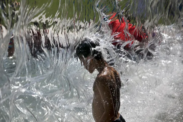 A child cools off in a wall of water on the first day of summer, Sunday, June 21, 2015, at Yards Park in Washington. (Photo by Jacquelyn Martin/AP Photo)