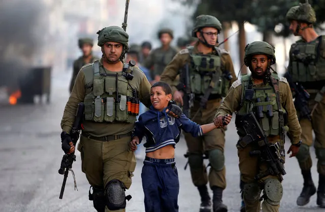 Israeli soldiers detain a Palestinian boy during clashes in the West Bank city of Hebron, October 13, 2017. (Photo by Mussa Qawasma/Reuters)