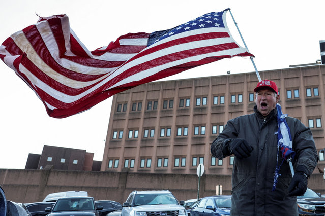 A man carries a U.S. flag outside a detention facility in Washington, on January 20, 2025. (Photo by Kevin Mohatt/Reuters)