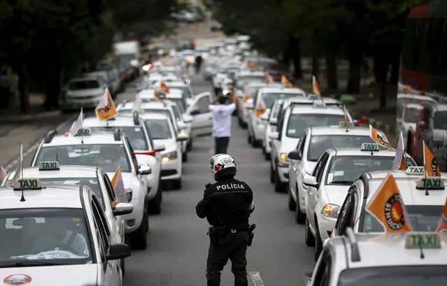A policeman walks between taxis drivers blocking an avenue to protest against the online car-sharing service Uber in Sao Paulo September 9, 2015. (Photo by Nacho Doce/Reuters)