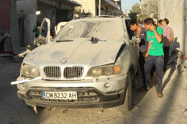 Residents inspect a damaged vehicle due to an airstrike in the rebel held town of Sarmada, near the Syrian-Turkish border, Idlib province, Syria July 21, 2016. (Photo by Ammar Abdullah/Reuters)