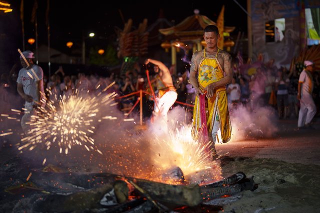 A worshippers lights firecrackers after walking over burning wood and coals barefoot during the Nine Emperor Gods festival at a temple in Kuala Lumpur, Malaysia, Monday, October 7, 2024. (Photo by Vincent Thian/AP Photo)