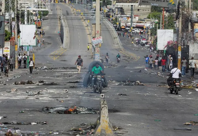 People pass through an empty street with remains of barricades during a nationwide strike against rising fuel prices, in Port-au-Prince, Haiti on September 26, 2022. (Photo by Ralph Tedy Erol/Reuters)