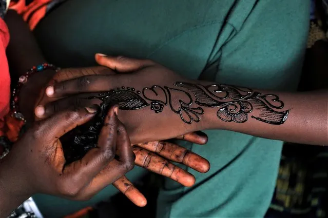 Bintou Diarra 21, makes henna tattoos on a girl's hand ahead of Eid al-Fitr, amid the spread of the coronavirus disease (COVID-19) in Adjame a neighbourhood of Abidjan, Ivory Coast on May 22, 2020. (Photo by Thierry Gouegnon/Reuters)
