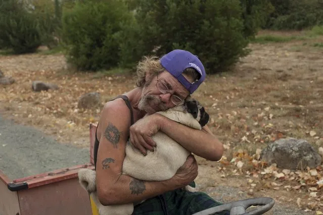 Robert Hooper, exhausted after several days with little sleep, hugs his dog Toby on his property that was partially burnt by the so-called Valley Fire near Middleton, California September 14, 2015. (Photo by David Ryder/Reuters)