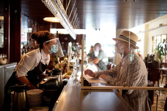 A bartender talks to a patron at Lemeac restaurant on the first day after novel coronavirus restrictions were lifted to visit restaurants in Montreal, Quebec, Canada on June 22, 2020. (Photo by Christinne Muschi/Reuters)