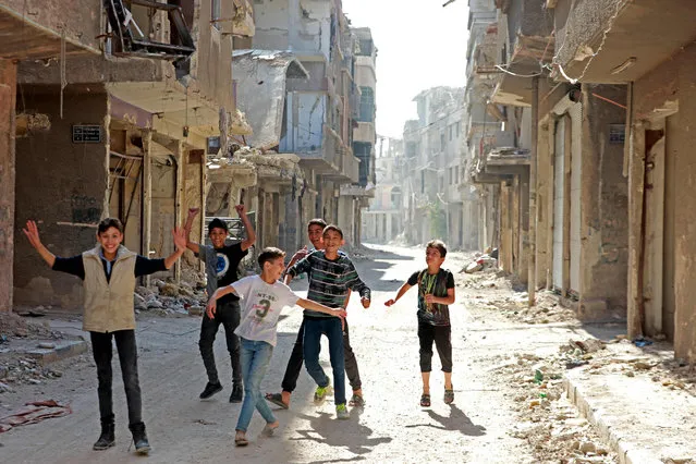 Boys play amid destroyed buildings at the Yarmuk refugee camp in the southern suburbs of the Syrian capital Damascus on November 2, 2022. The regime of Syria's President Bashar al-Assad has recaptured vast territory from rebels and jihadists in the conflict that began in 2011, including retaking the Palestinian camp and adjacent suburbs in May 2018, after a pulverising assault that lasted nearly a month. (Photo by Louai Beshara/AFP Photo)