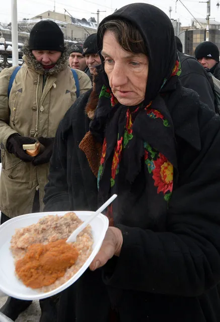 Homeless people  queue to get free hot food organized by social services during frost winter day in  Kiev on December 18, 2012. Nineteen people died of exposure in Ukraine in the last 24 hours amid temperatures of minus 20 degrees Celsius (minus 4 degrees Fahrenheit), bringing the toll this month to 37, the health ministry said Tuesday. (Photo by Sergei Supinsky/AFP Photo)