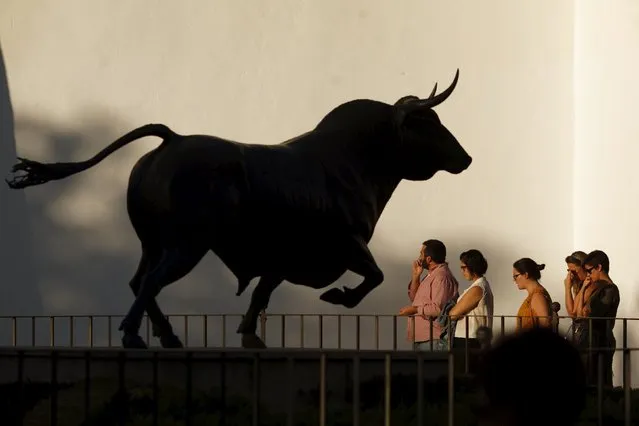 Tourists walk next to a statue of a bull outside a bullring during the World Tourism Day, in Ronda, southern Spain, September 27, 2015. (Photo by Jon Nazca/Reuters)