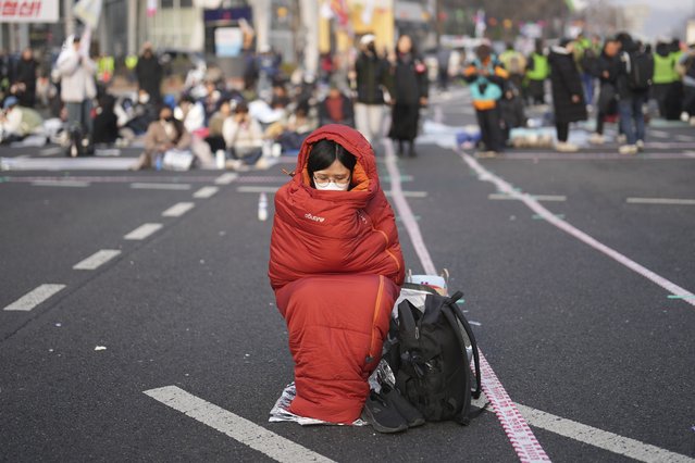 Jo Eun-jin, who stayed overnight on the street, waits for the start of a rally calling for impeached South Korean President Yoon Suk Yeol to step down, near the Constitutional Court in Seoul, South Korea, Friday, April 4, 2025. (Photo by Lee Jin-man/AP Photo)