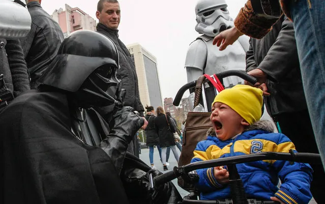 A candidate, presenting himself in the character of “Star Wars” villain Darth Vader and representing the Internet Party of Ukraine which runs for parliament, gestures in front of a crying boy during a meeting with his supporters and voters in Kiev, October 22, 2014. (Photo by Valentyn Ogirenko/AFP Photo)