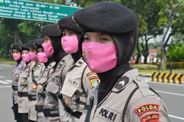 Indonesian police wearing face masks as a preventive measure against the COVID-19 coronavirus stand guard as workers protest against a bill on job creation they believe will deprive workers of their rights, outside the presidential palace in Jakarta on July 22, 2020. The Indonesian government has submitted the omnibus bill on job creation to the House of Representatives to boost economic growth, create jobs and investments. (Photo by Adek Berry/AFP Photo)
