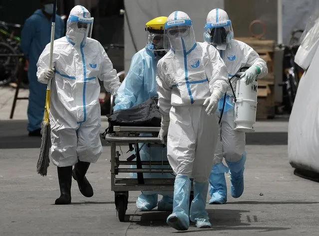 Health workers in protective suits transport a corpse at a hospital in Manila, Philippines, Thursday, August 6, 2020. The capital and outlying provinces returned to another lockdown after medical groups warned that the country was waging a losing battle against the coronavirus amid an alarming surge in infections. (Photo by Aaron Favila/AP Photo)
