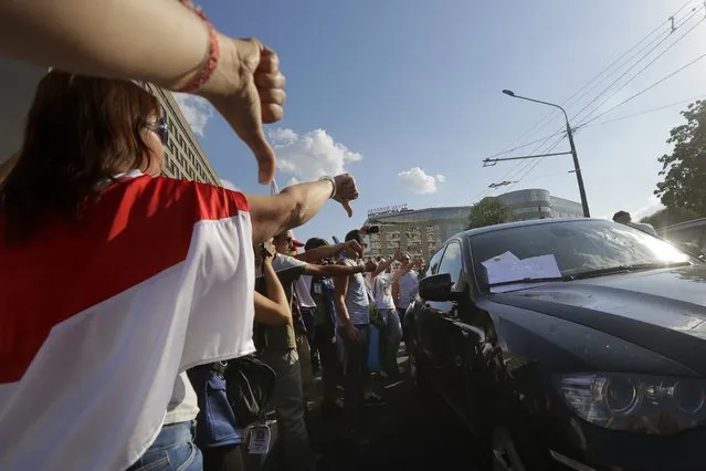 People gesture as they block a car carrying Uladzimir Karanik, Minister of Health of the Republic of Belarus during a rally in Minsk, Belarus, Monday, August 17, 2020. Workers heckled and jeered President Alexander Lukashenko on Monday as he visited a factory and strikes grew across Belarus, raising the pressure on the authoritarian leader to step down after 26 years in power. (Photo by Sergei Grits/AP Photo)