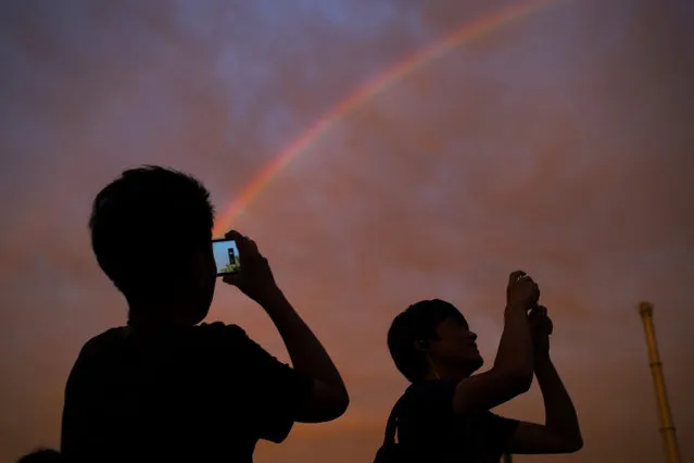 Passersby take photos of a rainbow at sunset in Beijing, Monday, August 3, 2015. (Photo by Mark Schiefelbein/AP Photo)