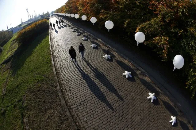 People walk under stands with balloons placed along the former Berlin Wall location at Mauerpark, which will be used in the installation “Lichtgrenze” (Border of Light) in Berlin November 7, 2014. (Photo by Pawel Kopczynski/Reuters)