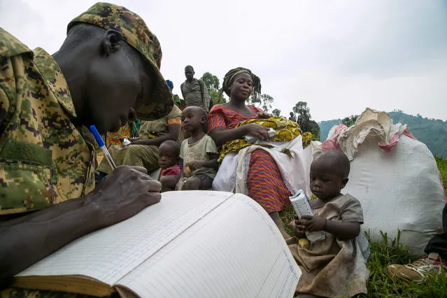 People are registered by a Ugandan soldier after they crossed the border from the Democratic Republic of Congo to be refugees at Nteko village in western Uganda on January 24, 2018. Since Last December, about 300 Congolese people per day, have been fleeing from the Mai Mai militias’ attacks in the Kivu region of the eastern part of DRC to this border area. (Photo by Sumy Sadurni/AFP Photo)
