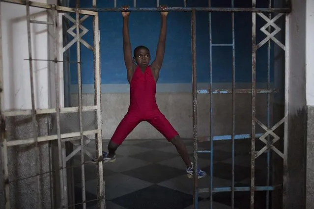 A child uses an iron door to exercise during a wrestling lesson in downtown Havana, October 29, 2014. (Photo by Alexandre Meneghini/Reuters)