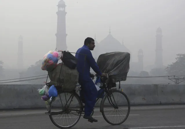 A cyclist passes by the historical Badshahi Mosque while smog envelopes the area in Lahore, Pakistan, Sunday, November 5, 2017. Smog has enveloped much of Pakistan and neighboring India, causing highway accidents and respiratory problems, and forcing many residents to stay home, officials said. (Photo by K.M. Chaudary/AP Photo)
