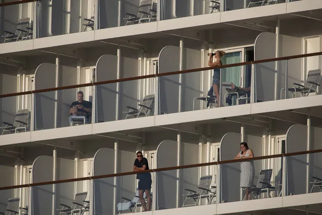 Passengers of the Mein Schiff 6 cruise ship stand outside their cabins as the ship is docked at Piraeus port, near Athens on Tuesday, September 29, 2020. Greek authorities say 12 crew members on a Maltese-flagged cruise ship carrying more than 1,500 people on a Greek islands tour have tested positive for coronavirus and have been isolated on board. (Photo by Petros Giannakouris/AP Photo)
