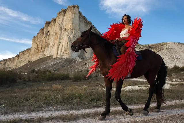 A model wearing a creation rides a horse during an outdoor fashion show for collections by Crimean designers near Ak-Kaya Rock in Belgorsk District of Crimea, Russia on September 13, 2020, during the 2020 Crimean Fashion Week. (Photo by Sergei Malgavko/TASS)