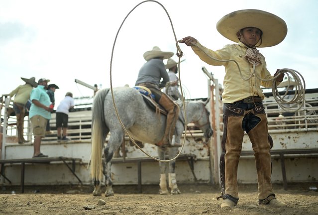 Jesus Rubio, 10, practices his lassoing routine before performing during the Mexican Rodeo Fiesta at the 156th Boulder County Fair on August 10, 2025 in Longmont, Colorado. The oldest county fair in Colorado, it focuses on family-oriented activities, the region's agricultural tradition, and showcases the projects of its 4-H and FFA youth, while remaining one of only four non-profit county fairs in the state. (Photo by Mark Makela/Getty Images)