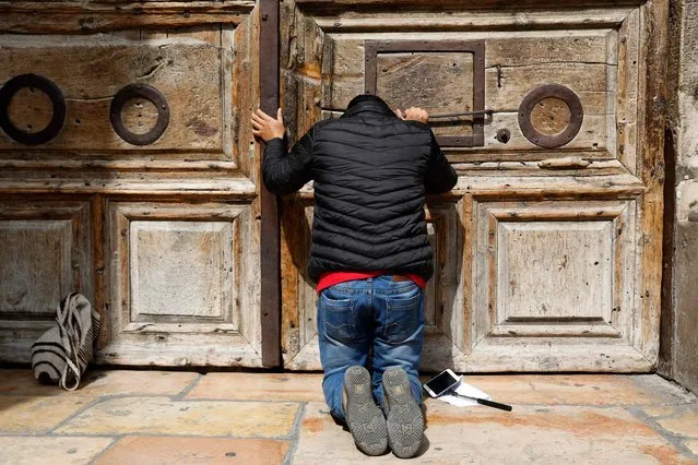 A pilgrim prays outside the closed gate of the Church of the Holy Sepulchre in Jerusalem's Old City on February 25, 2018. Christian leaders took the rare step of closing the Church of the Holy Sepulchre, built at the site of Jesus's burial in Jerusalem, in protest at Israeli tax measures and a proposed property law. (Photo by Gali Tibbon/AFP Photo)