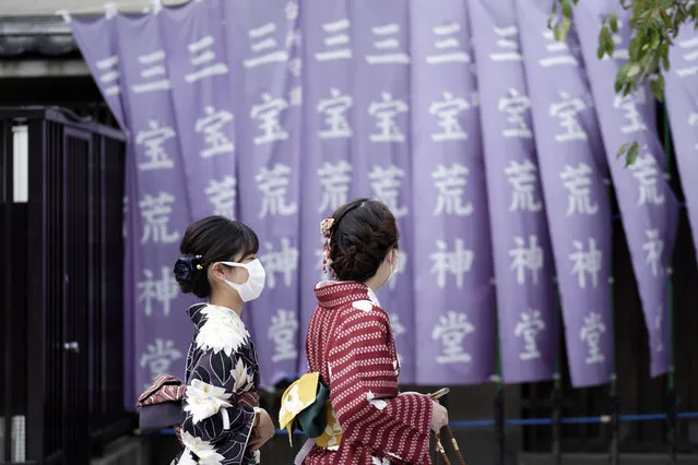 Kimono-clad visitors wearing protective masks to help curb the spread of the coronavirus walk at a shopping arcade at Asakusa district Thursday, October 22, 2020, in Tokyo. (Photo by Eugene Hoshiko/AP Photo)