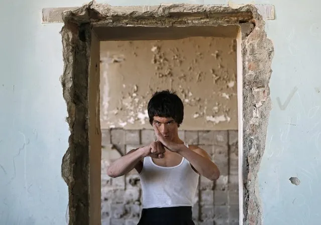 Abbas Alizada, who calls himself the Afghan Bruce Lee, poses during a media event in Kabul December 9, 2014. From the ruins of an iconic bombed-out palace above Kabul, the young Afghan man bearing a striking resemblance to kung fu legend Bruce Lee is high-kicking his way to Internet fame, aiming to show another side to his war-weary nation. (Photo by Mohammad Ismail/Reuters)