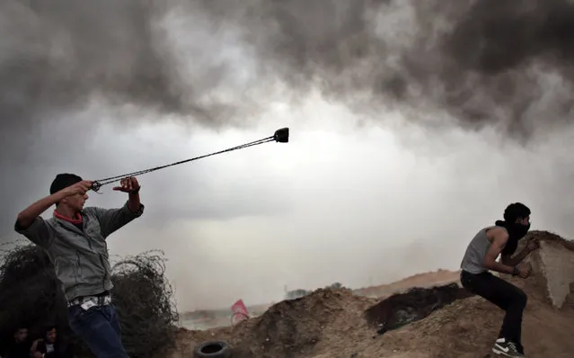 A Palestinian protester hurls stones using a sling shot during clashes with Israeli soldiers on the Israeli border with Gaza in Bureij, central Gaza Strip, Friday, November 6, 2015. (Photo by Khalil Hamra/AP Photo)