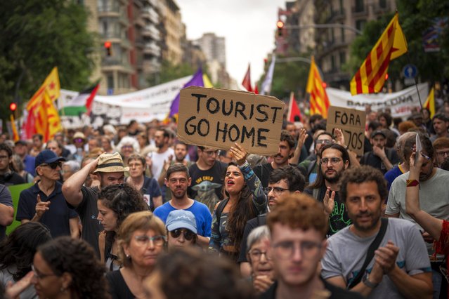 Demonstrators march shouting slogans against the Formula 1 Barcelona Fan Festival in downtown Barcelona, Spain, Wednesday, June 19, 2024. Around 500 Barcelona residents protest against mass tourism during an exhibition of Formula One race cars in the Spanish city. (Photo by Emilio Morenatti/AP Photo)