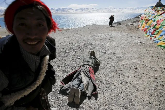 A Tibetan looks at the camera as other one prostrates himself above Namtso lake in the Tibet Autonomous Region, China November 17, 2015. (Photo by Damir Sagolj/Reuters)