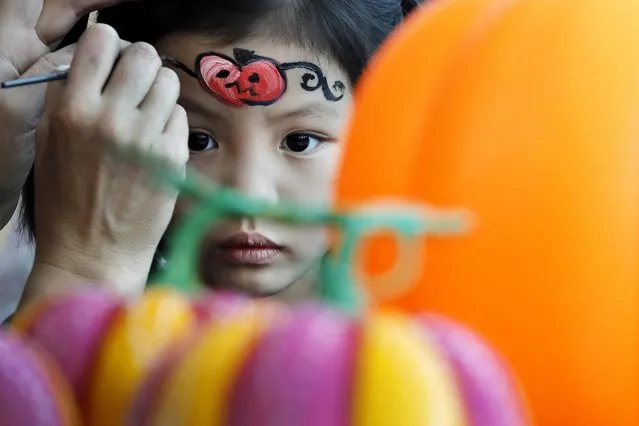 A girl gets face painted by an artist during an activity ahead of Halloween at a shopping mall in Beijing, Saturday, October 29, 2016. (Photo by Andy Wong/AP Photo)