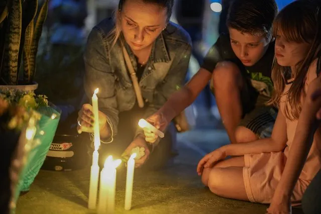 A woman and a child light candles outside the “Cantinho do Bom Pastor” daycare center after a fatal attack on children in Blumenau, Brazil, Wednesday, April 5, 2023. A man with a hatchet jumped over a wall and burst into a day care center Wednesday in Brazil, killing four children and wounding at least four others, authorities said. (Photo by Andre Penner/AP Photo)