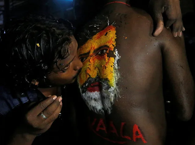 A fan kisses an image of actor Rajinikanth painted on the body of another as they celebrate the release of his new movie “Kaala” in Mumbai, India, June 7, 2018. (Photo by Francis Mascarenhas/Reuters)